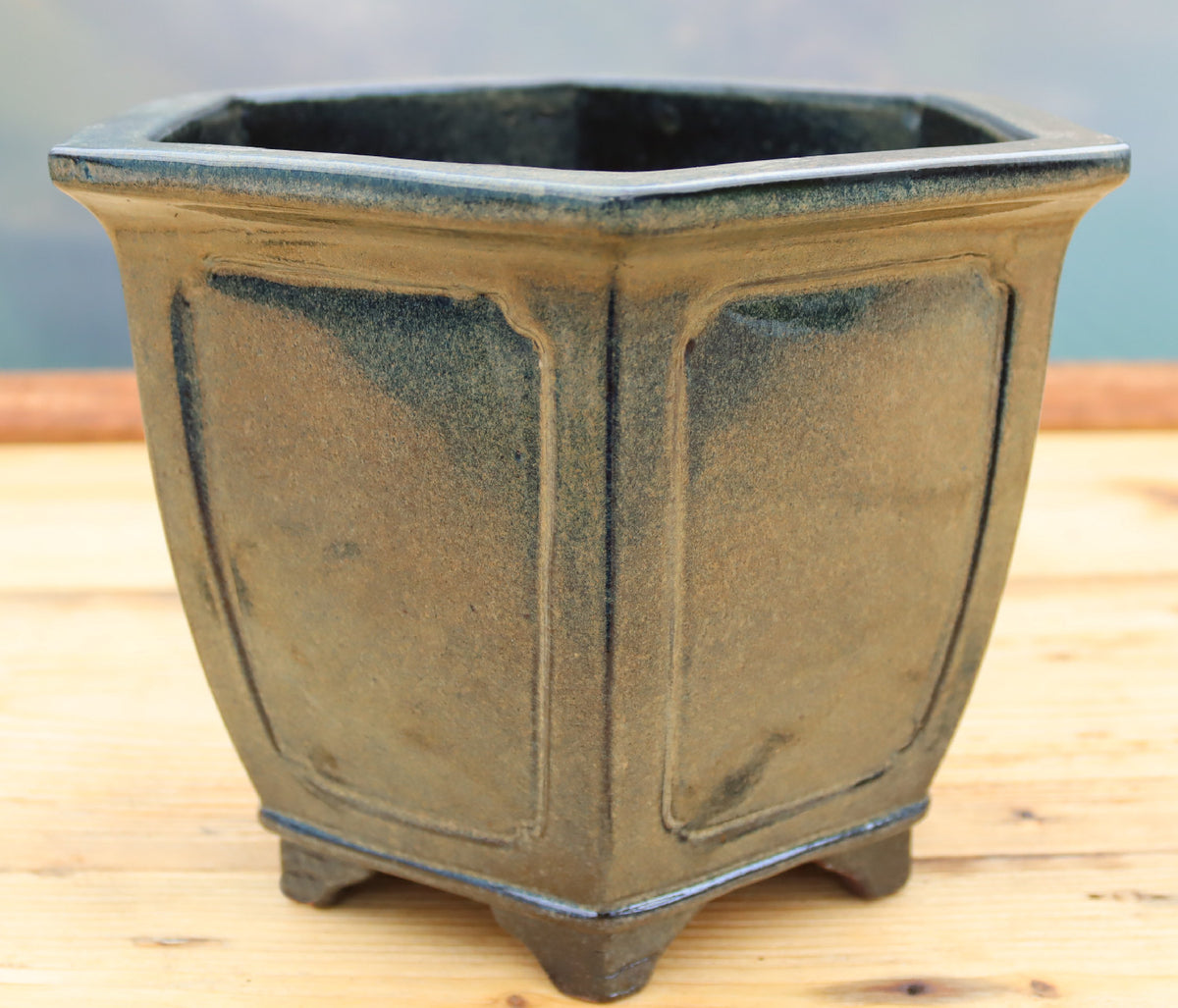 A dark grey/green glazed ceramic hexagonal bonsai pot with raised panel details and small feet.