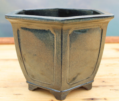 A dark grey/green glazed ceramic hexagonal bonsai pot with raised panel details and small feet.