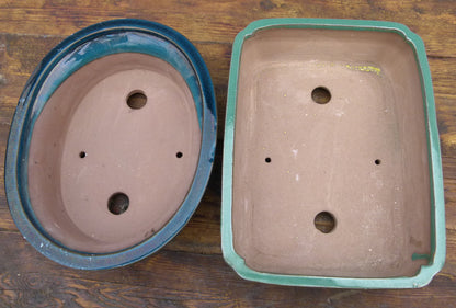 Two ceramic bonsai trays on a wooden surface
